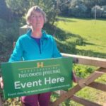 Parish Councillor Sarah Aitken stood holding a sign to welcome guests to the Herefordshire Histories Festival event